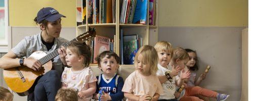 Preschool teacher playing guitar for students