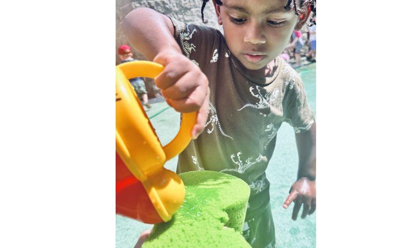 Preschooler pouring water in a water playground