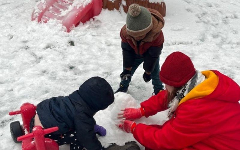 Preschoolers building a snowman together