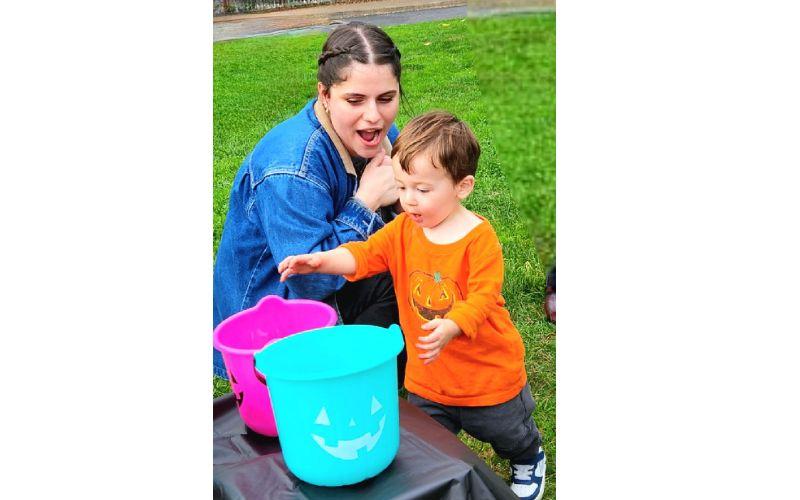 Preschooler and teacher playing with trick-or-treat buckets
