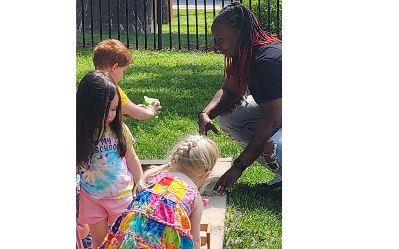 Teacher engaging with children in a sandbox