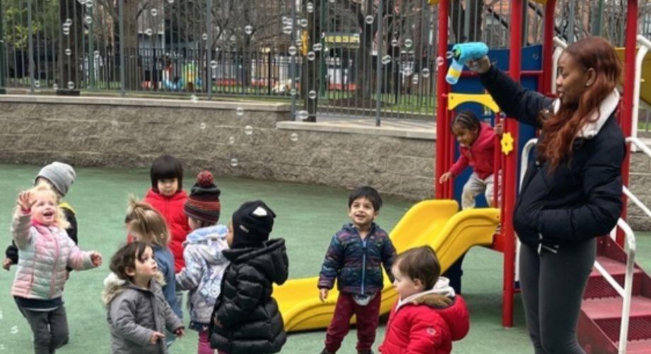Preschool teacher blowing bubbles on a playground